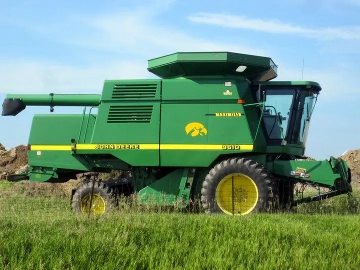 A green John Deere 9610 combine in a field